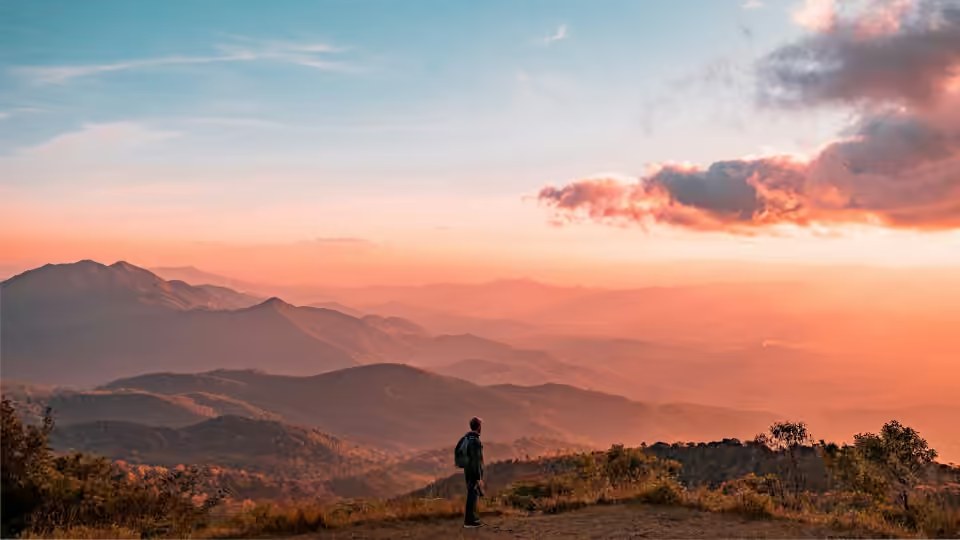 Una persona in contemplazione davanti all’alba, tra le montagne